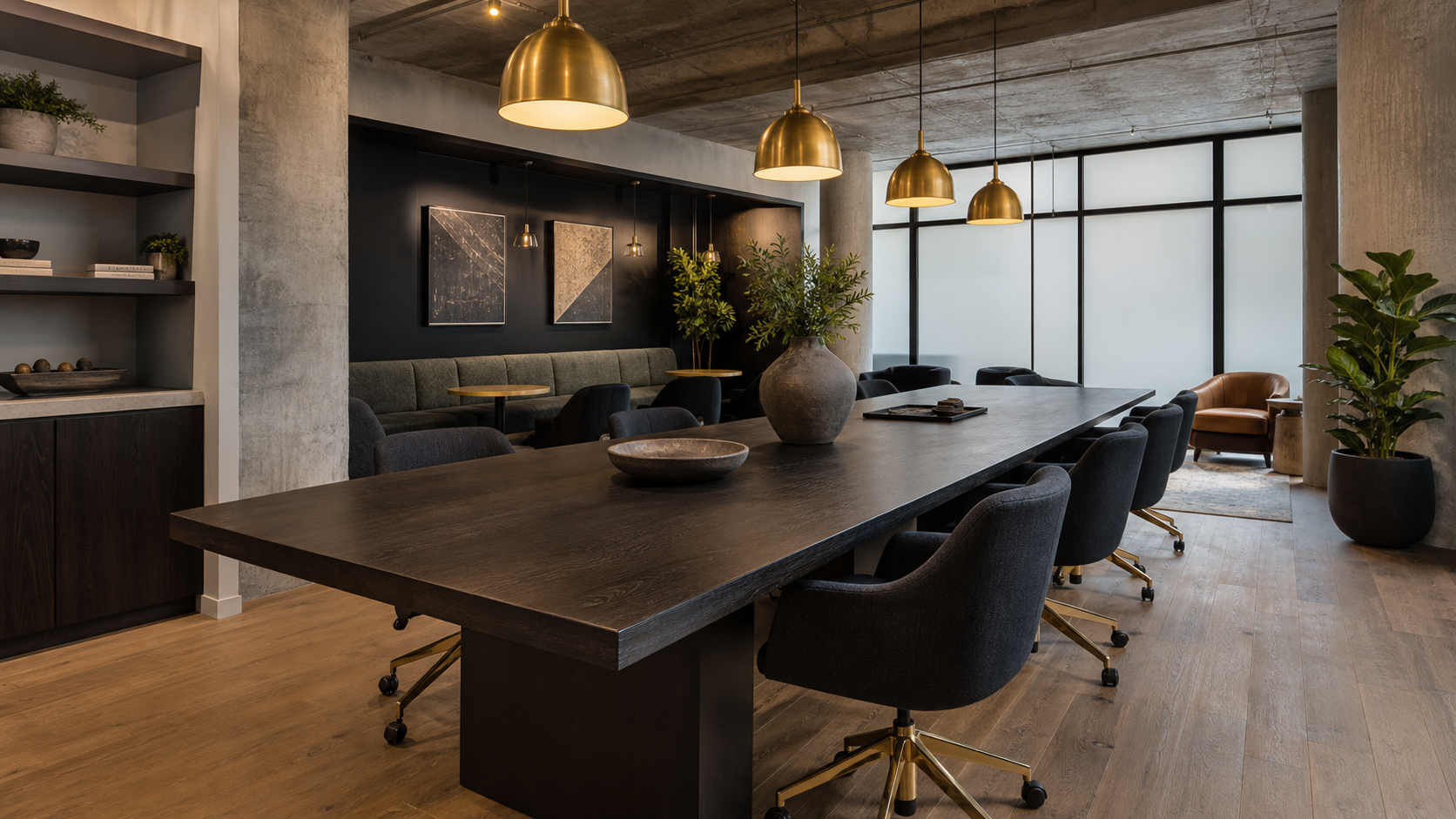 Multifamily coworking lounge with contract-grade task seating and wood communal tables, dark charcoal and brass palette